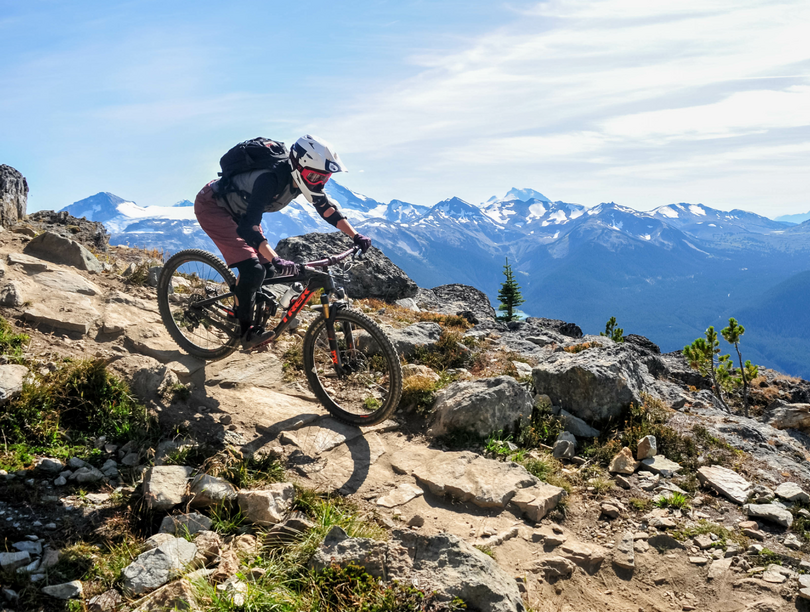 Mountain biker riding bike on rocky path overlooking mountains