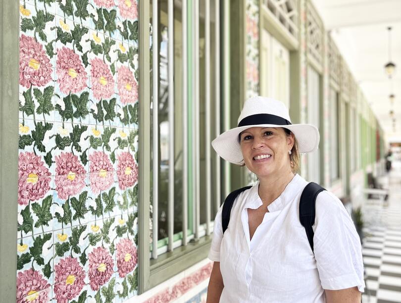 Suzanne Scott headshot, with an angled view of a terrace house with a floral print in the backdrop
