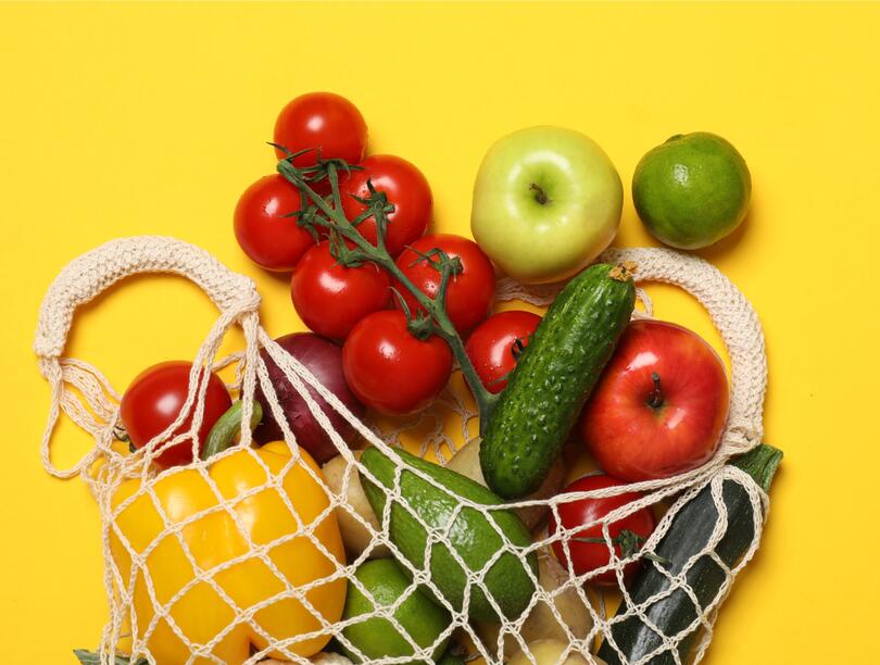 Vegetables in a mesh grocery bag against a yellow background