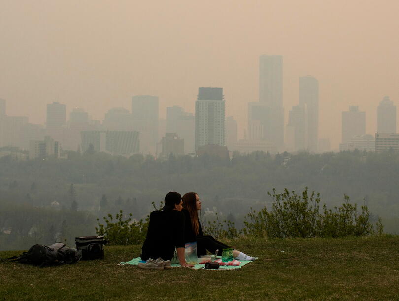 Couple having a picnic with smog-clouded city skyline in background