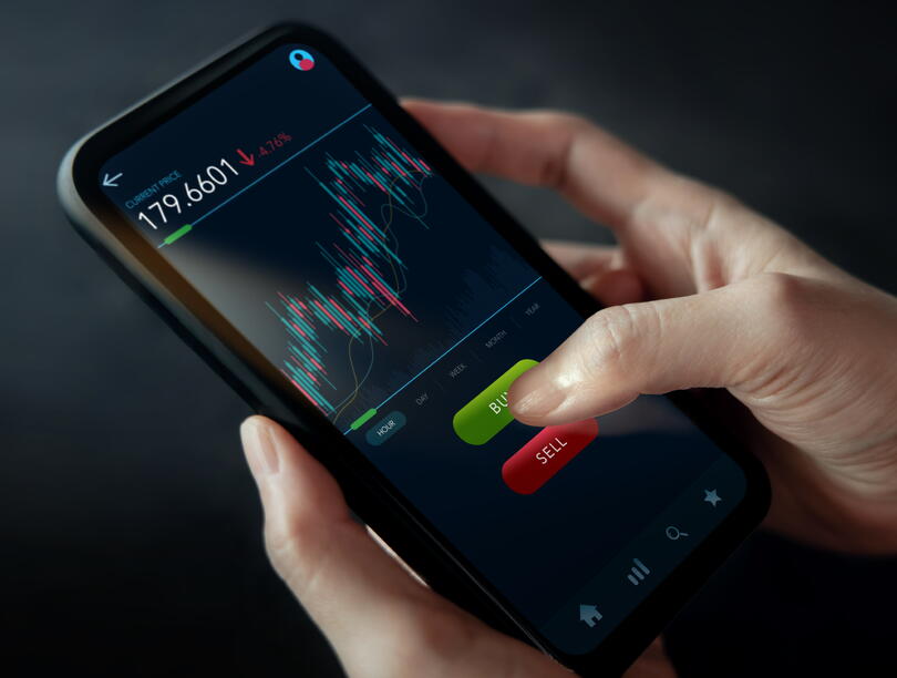 Woman's hands on smartphone displaying stock market graphics