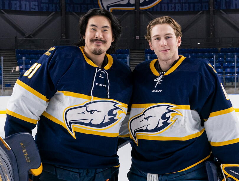 Two hockey players stand side by side in ice rink