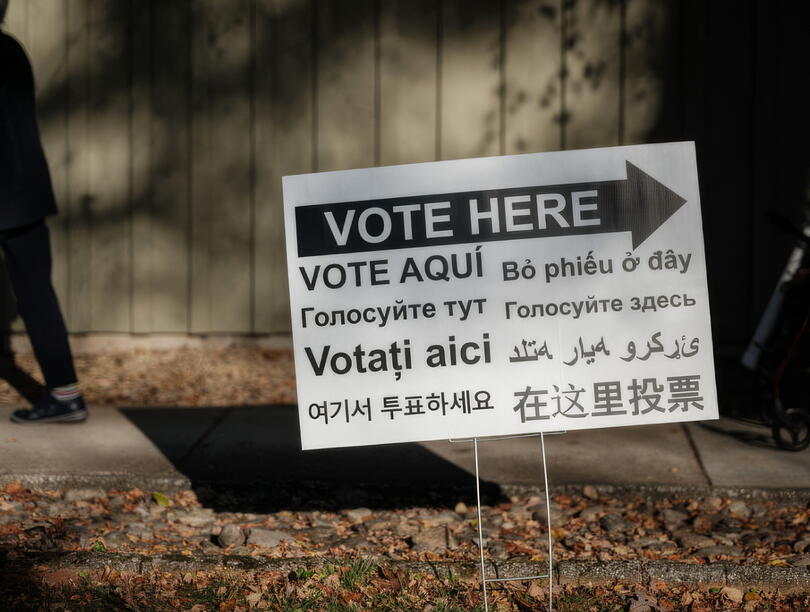 A signboard in multiple languages with directions to voting station 