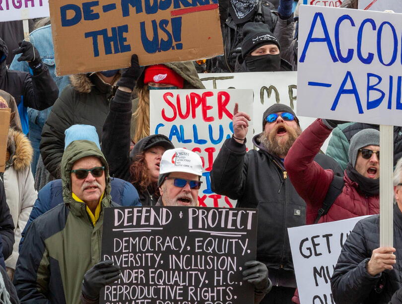Photo of people protesting and holding up signs. One sign says: "Accountability."