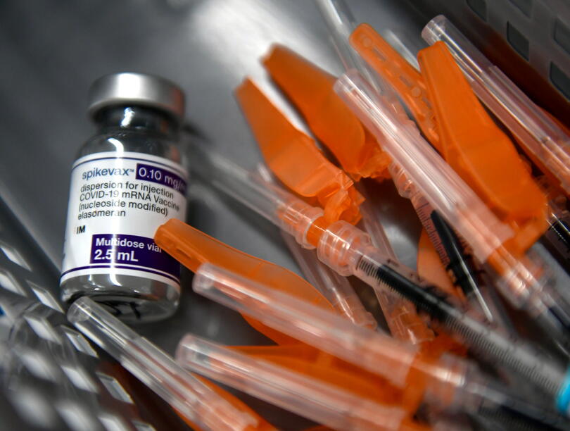 A vaccine bottle beside several syringes