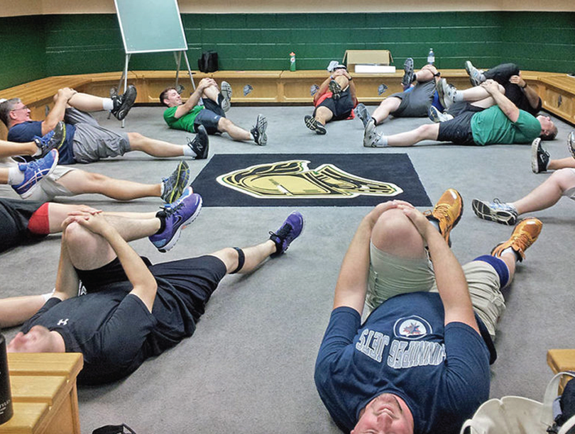 Men doing stretches lying on floor of a changeroom