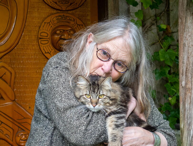 A photo of Susan Musgrave clutching a cat to her chest