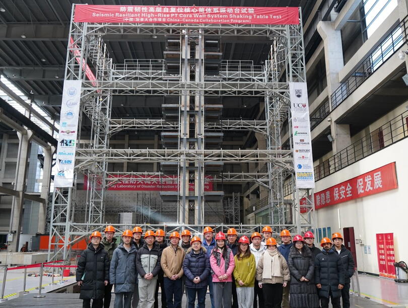Group of people wearing hardhats in front of scaffolding structure