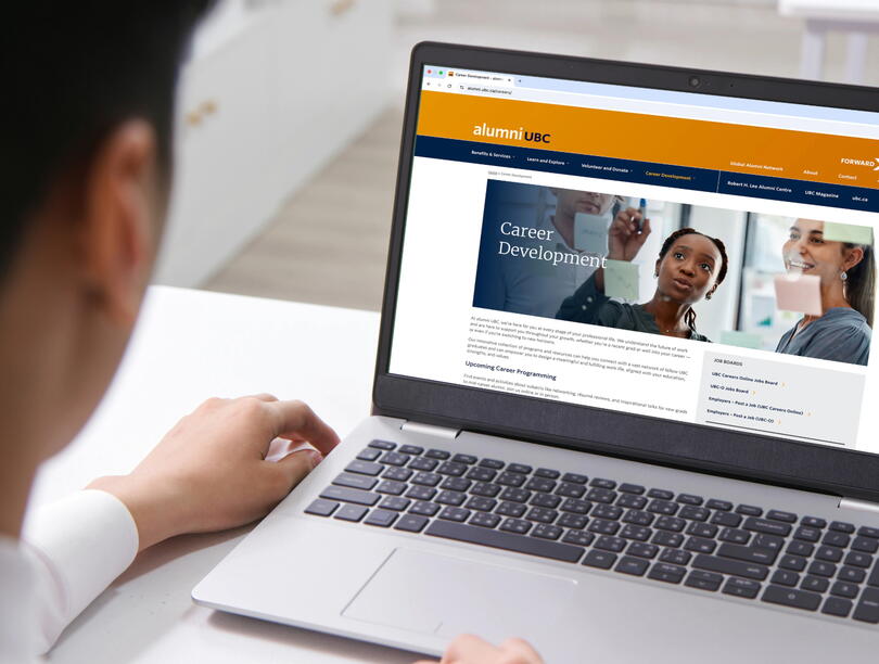 Over-the-shoulder shot of a person looking at the alumni UBC Career Development page on a laptop