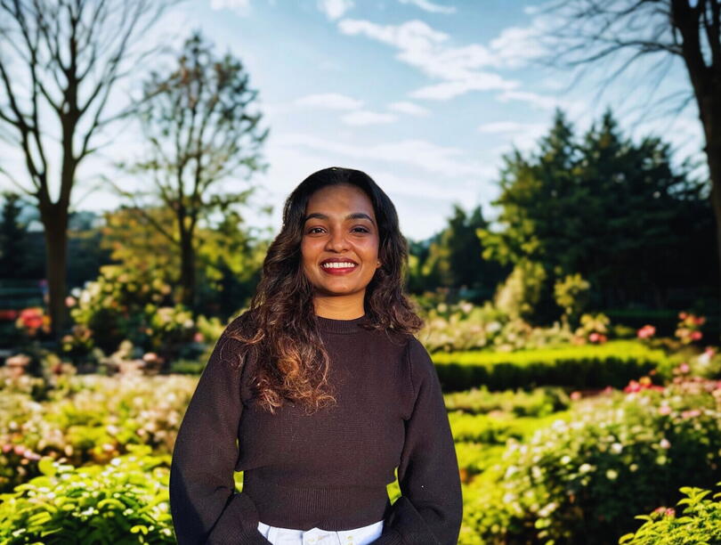 Smiling woman standing against a garden backdrop