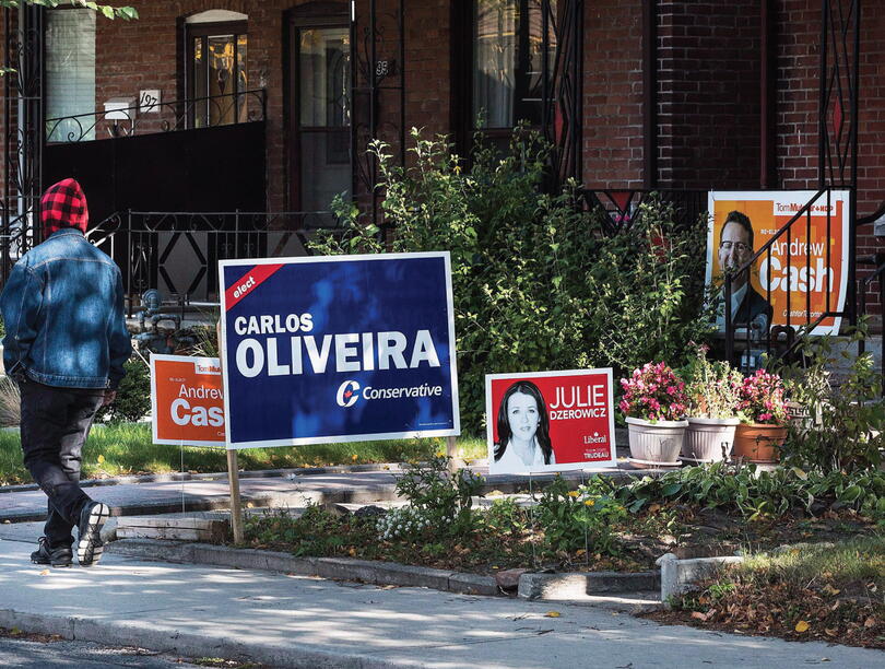 Campaign signs on a lawn as a person walks by