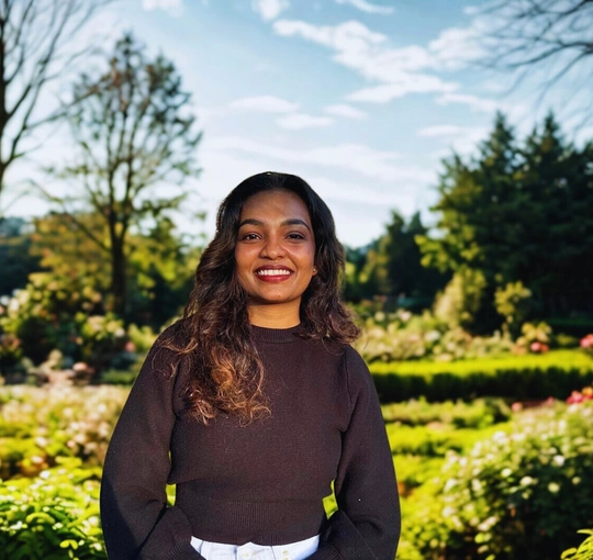 Smiling woman standing against a garden backdrop