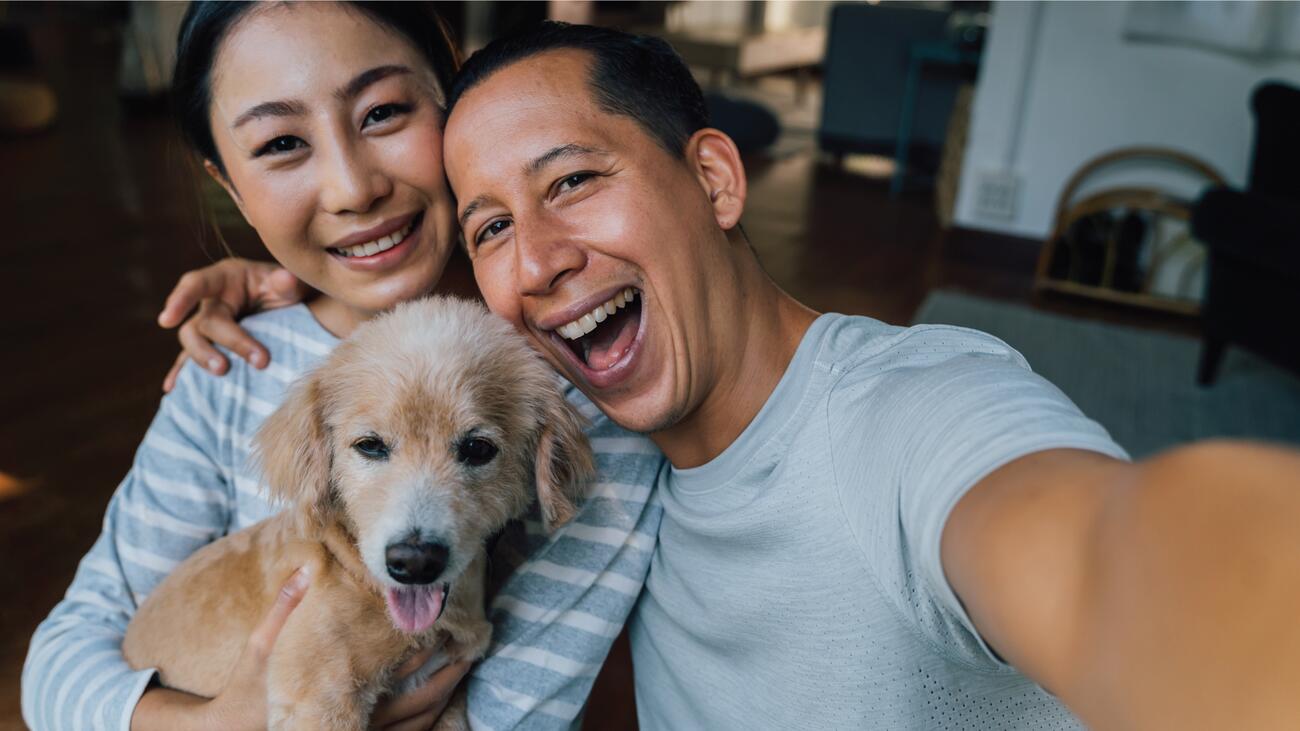 A couple taking a selfie with their puppy