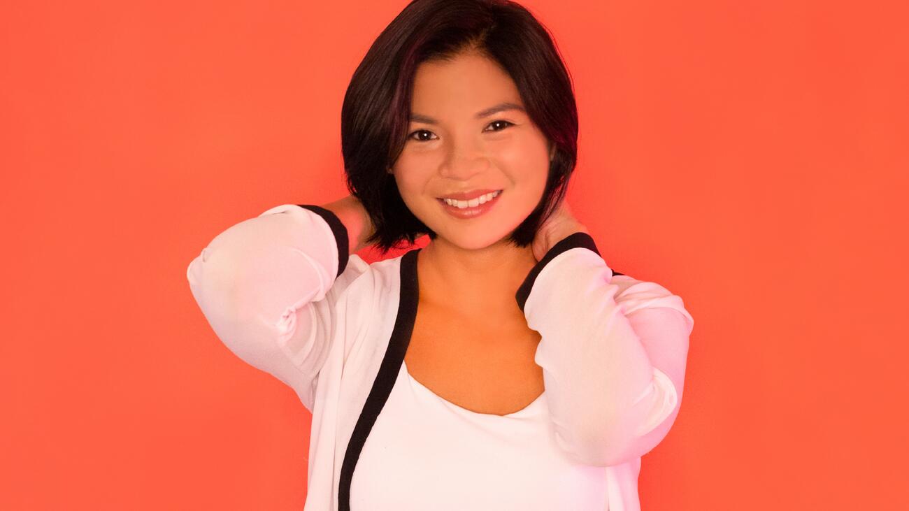 A picture of Kookai Chaimahawong, smiling, against an orange background.