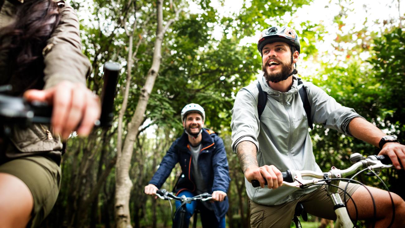 Three men on bikes cycling through a forest