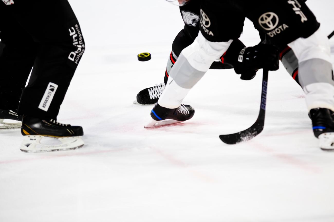 Legs of hockey players and referee on ice as puck drops