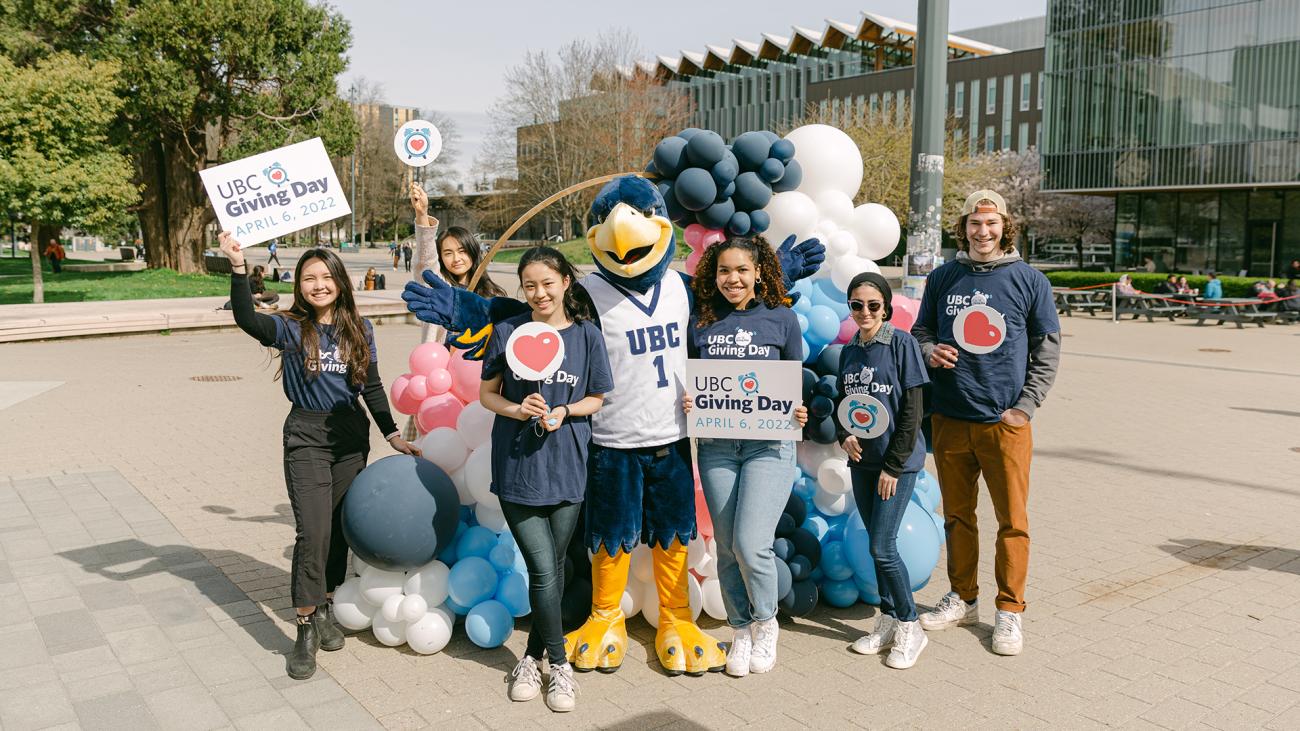 Students and staff holding UBC Giving Day signs and balloons on Vancouver campus