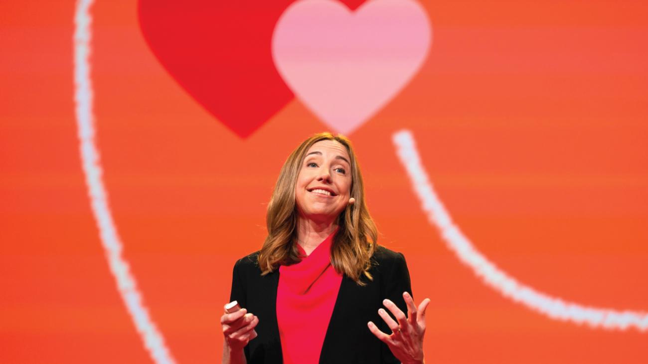 Photo of Dr. Elizabeth Dunn on a stage with a red background