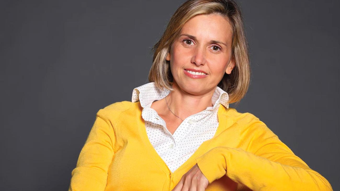 Elena Giorgetti in a yellow sweater against a grey background.