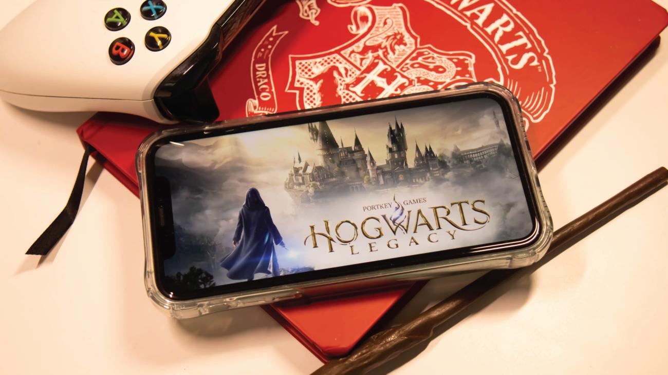 Hogwarts Legacy game displayed on smartphone beside game controller