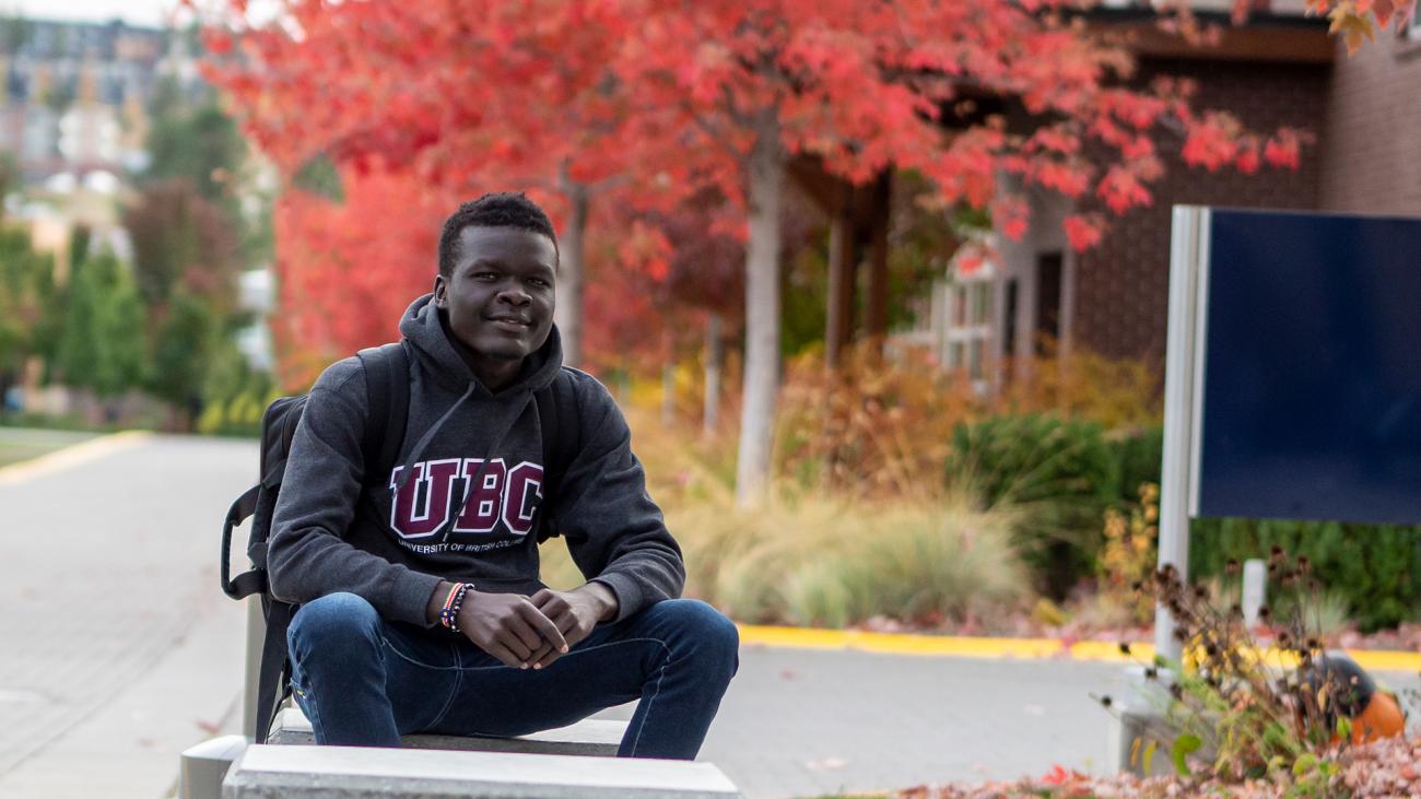 Headshot of James Magok Achuli seated outdoors on UBCO campus on a fall day