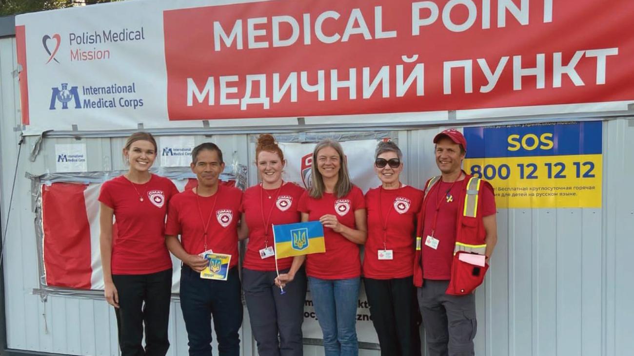 Six health-care workers stand in front of wall with Ukrainian signs