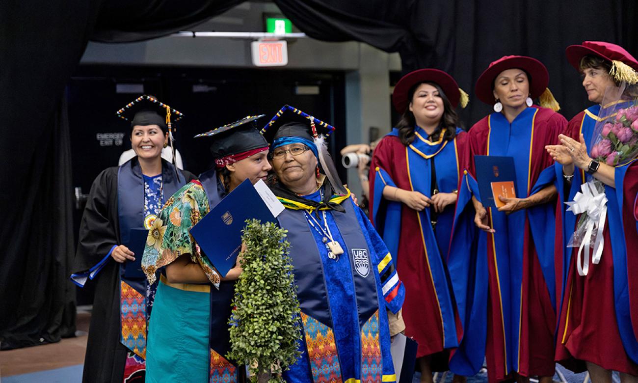 Six women on graduation stage in university regalia