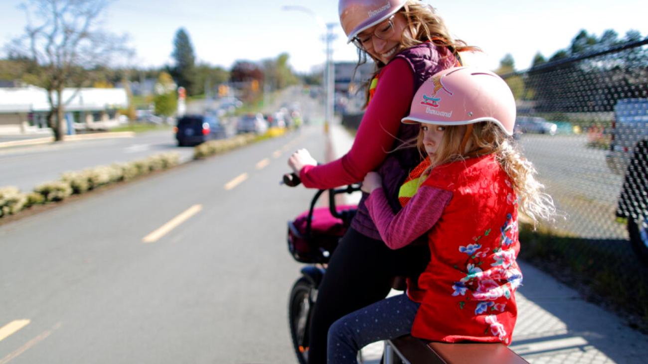 Woman and young girl wearing helmets on bicycle on street