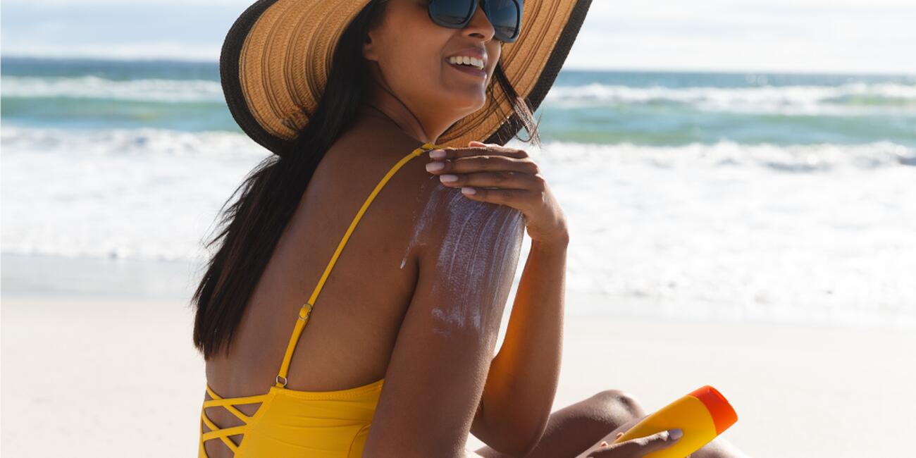 Woman at beach applying sunscreen on herself