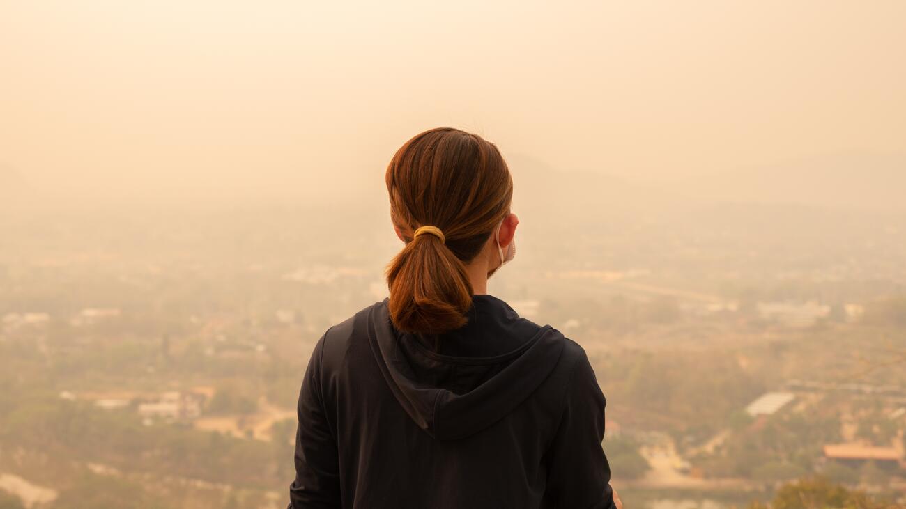 Woman sitting facing city shrouded in haze