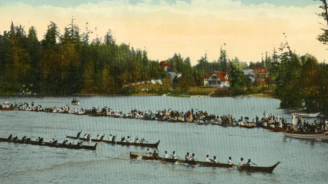 Canoes race past boats with onlookers in Victoria, B.C.