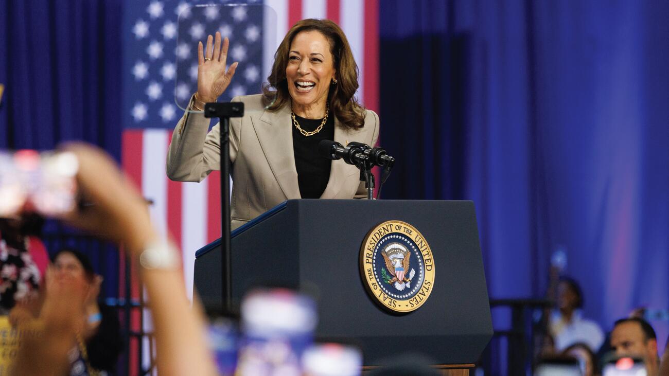 Kamala Harris waves to crowd from podium in front of US flag