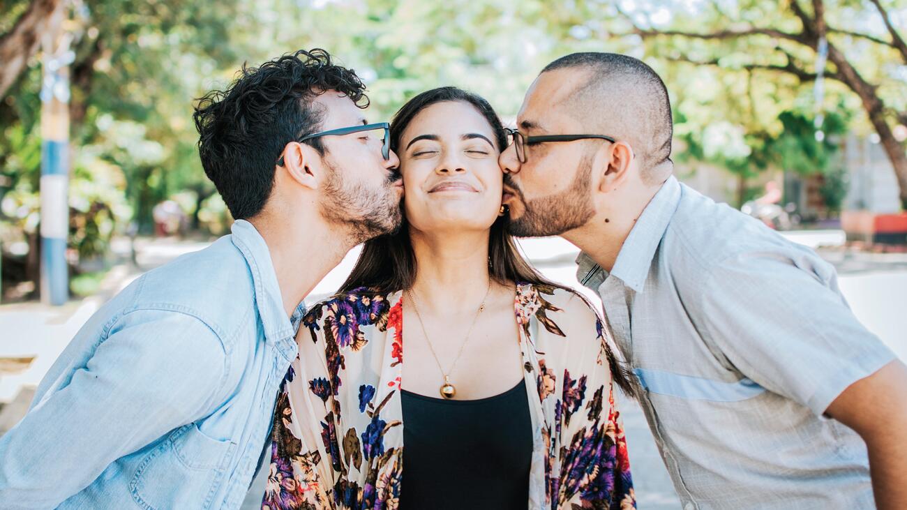 A woman being kissed on either cheek by two people