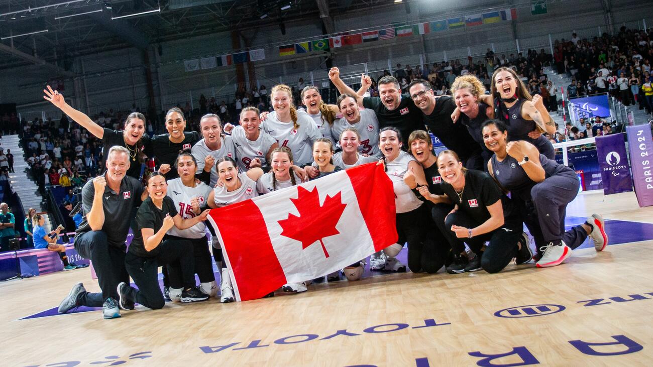 Athletic team cheering and holding Canadian flag in a gym