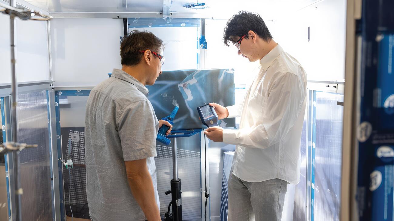 Two men look at device in an industrial lab 