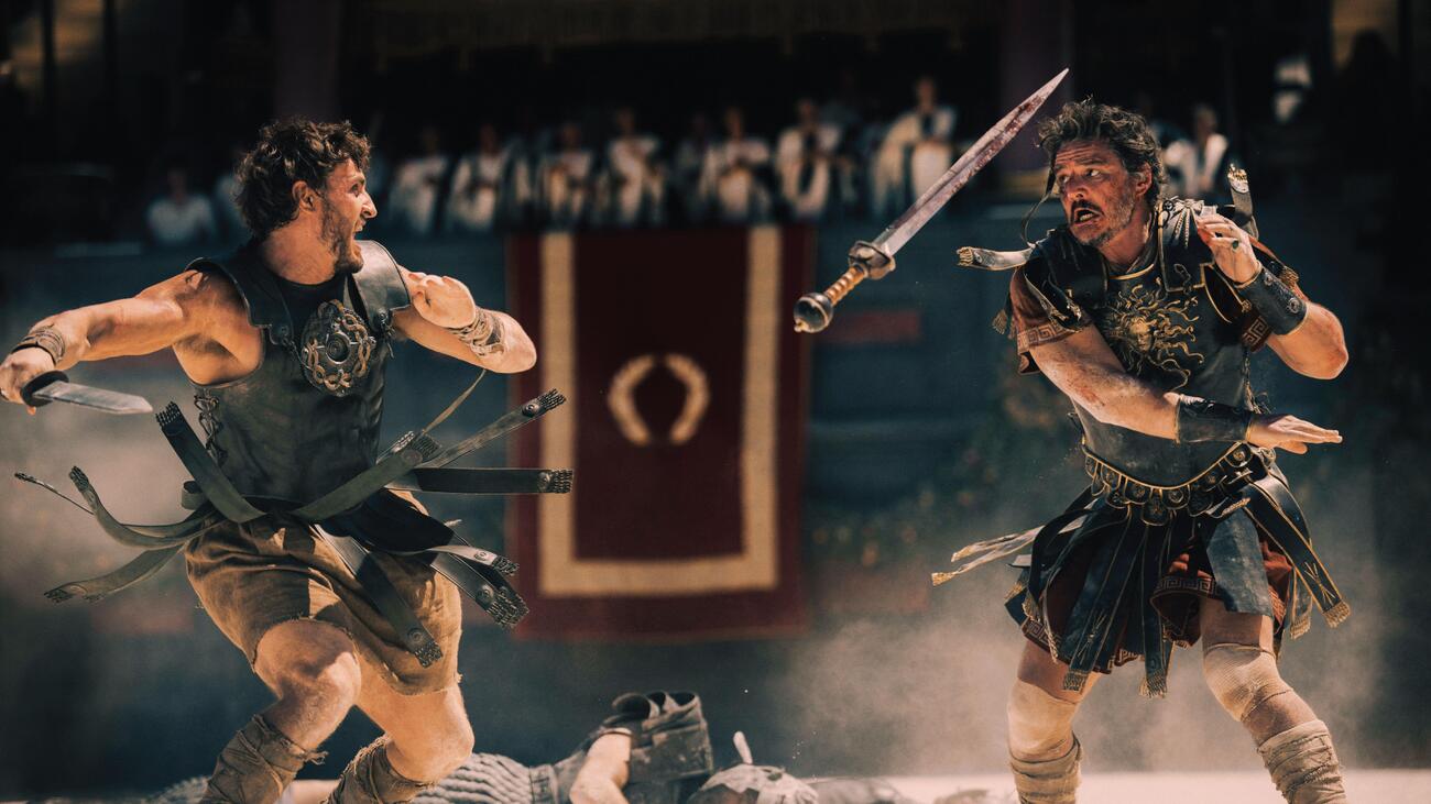 Two male gladiators battle with swords in arena