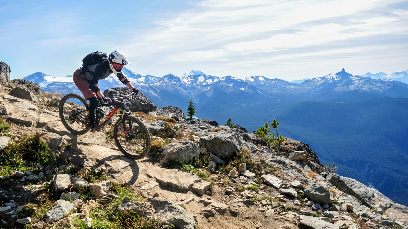 Mountain biker riding bike on rocky path overlooking mountains