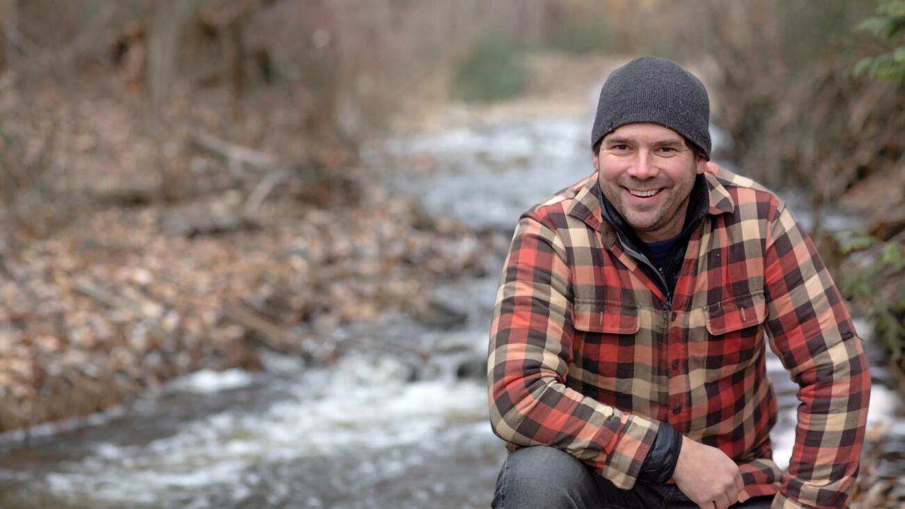 Dr. Adam Ford outdoors, with a creek behind him