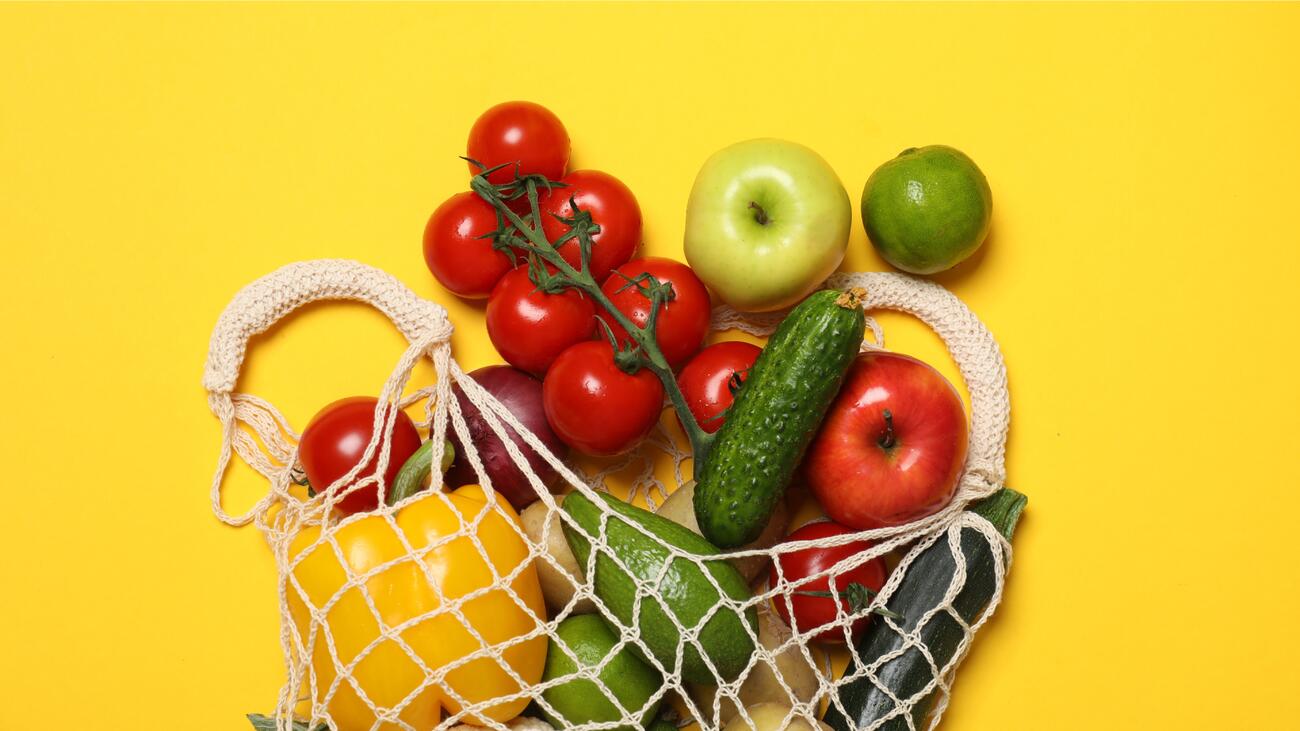 Vegetables in a mesh grocery bag against a yellow background