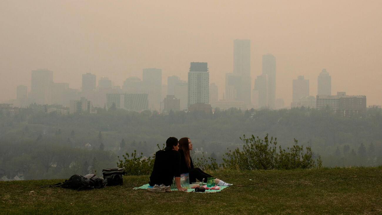 Couple having a picnic with smog-clouded city skyline in background