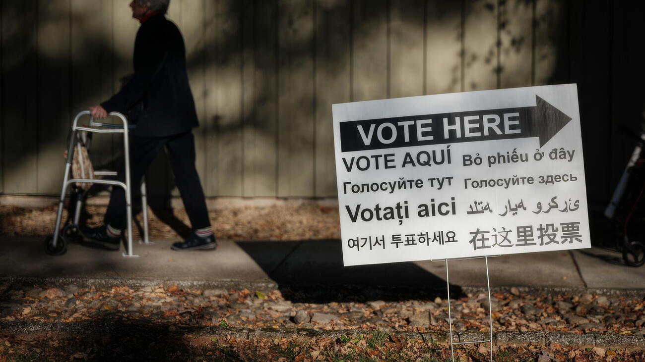 A signboard in multiple languages with directions to voting station 