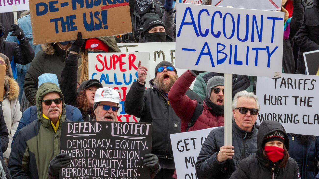 Photo of people protesting and holding up signs. One sign says: "Accountability."