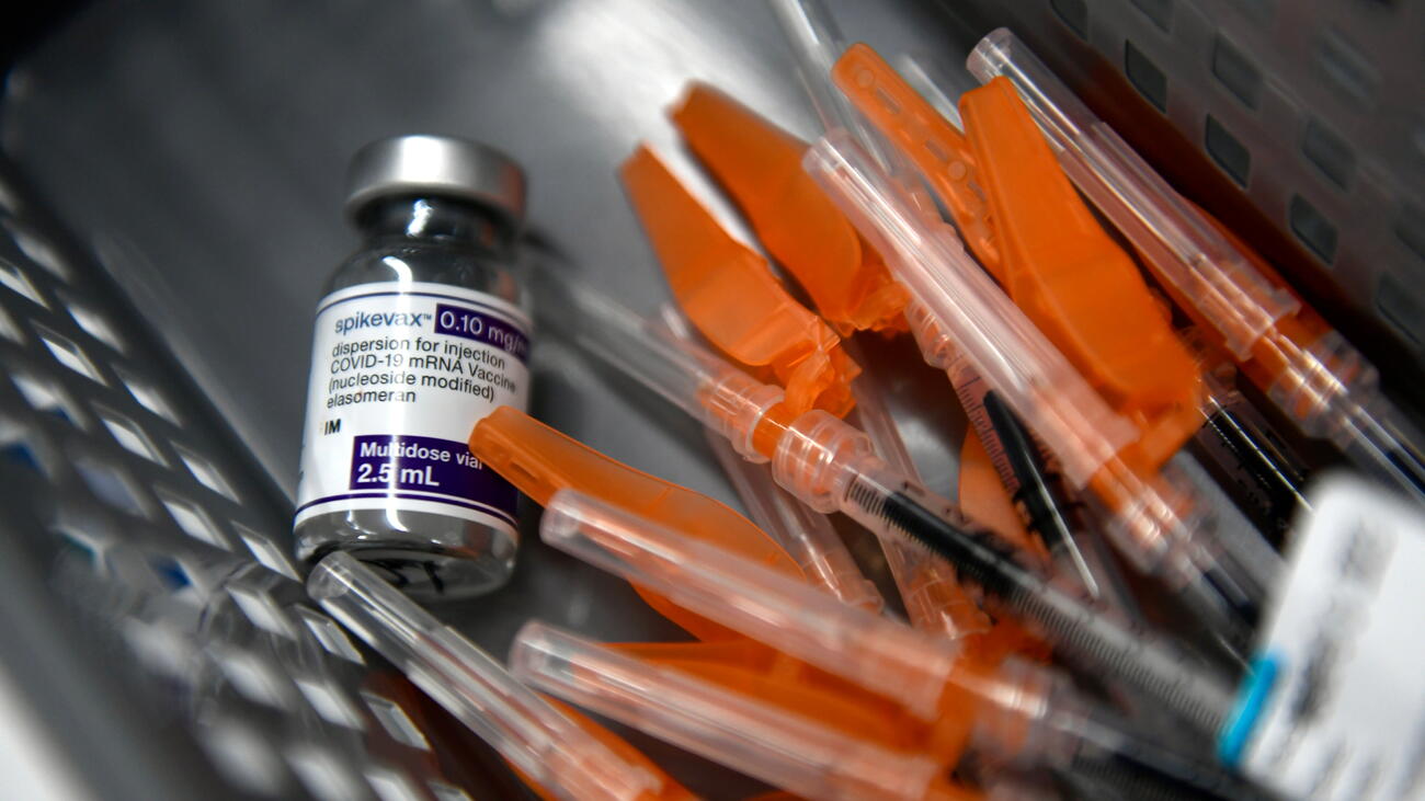 A vaccine bottle beside several syringes