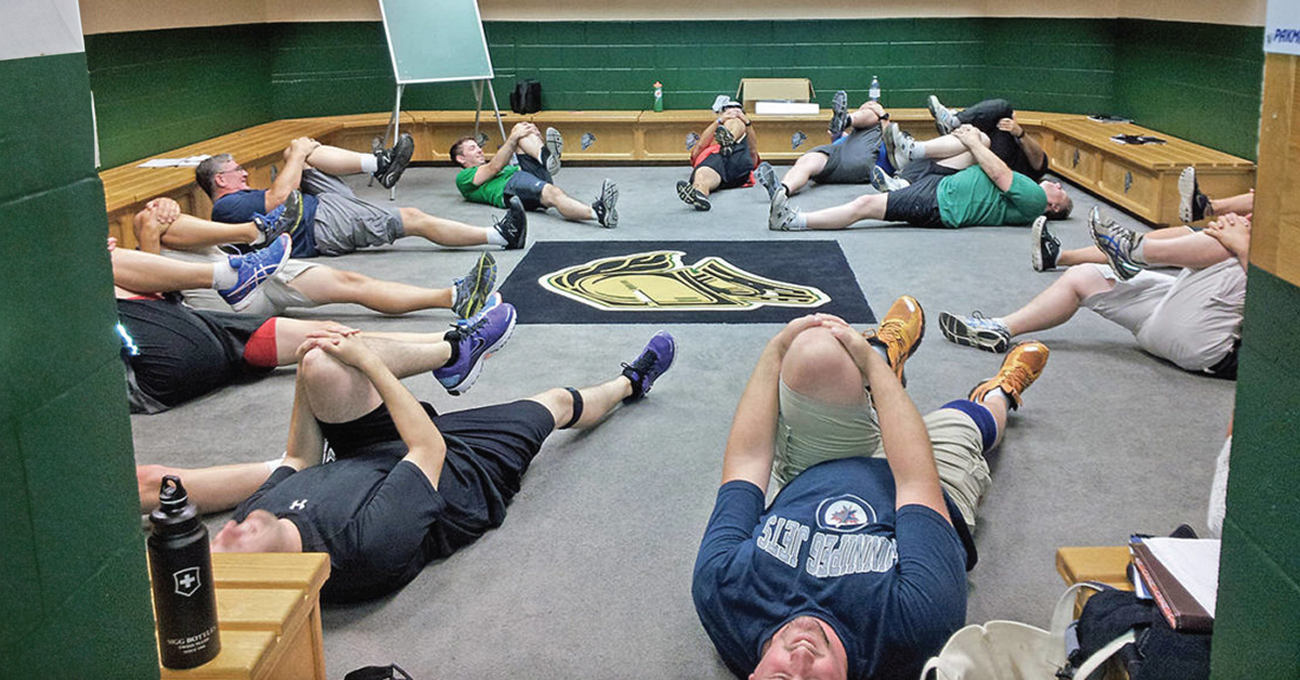 Men doing stretches lying on floor of a changeroom