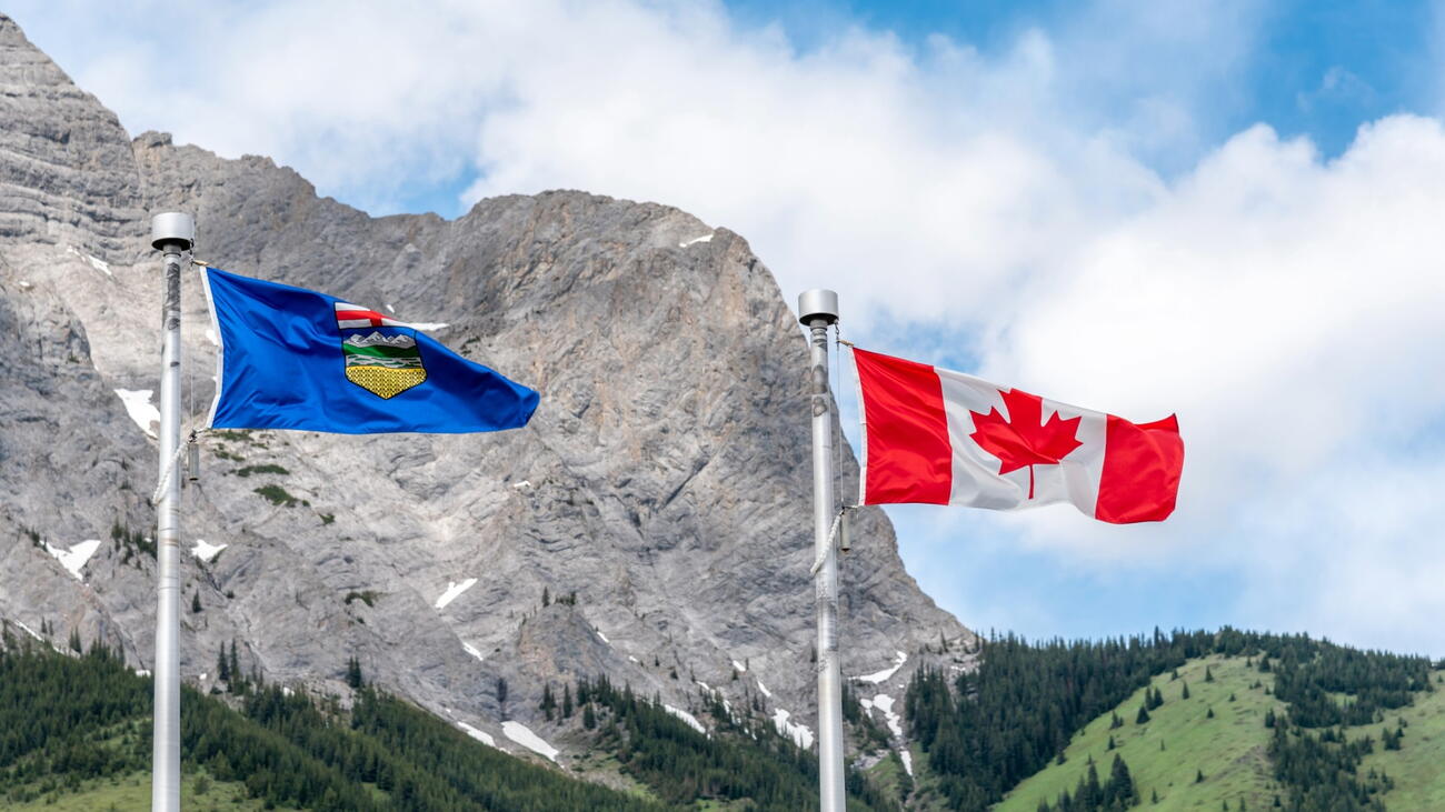 Alberta and Canadian flags in front of mountains