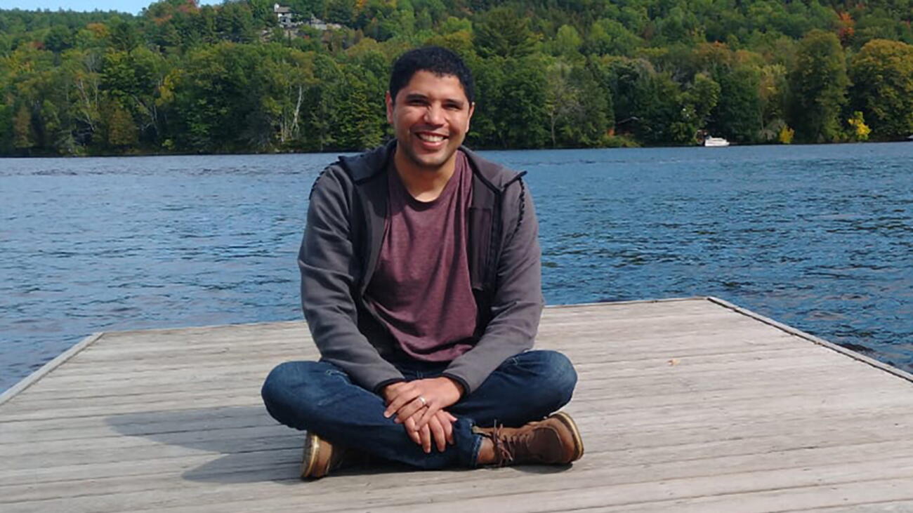 Hugo Mota Santos seated on a deck with water and trees in the background