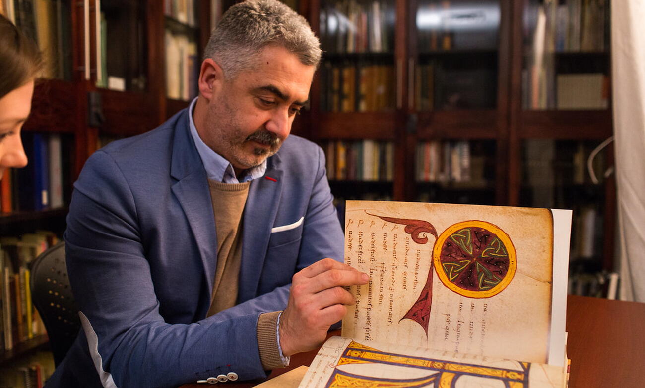 Man looks at large book in library