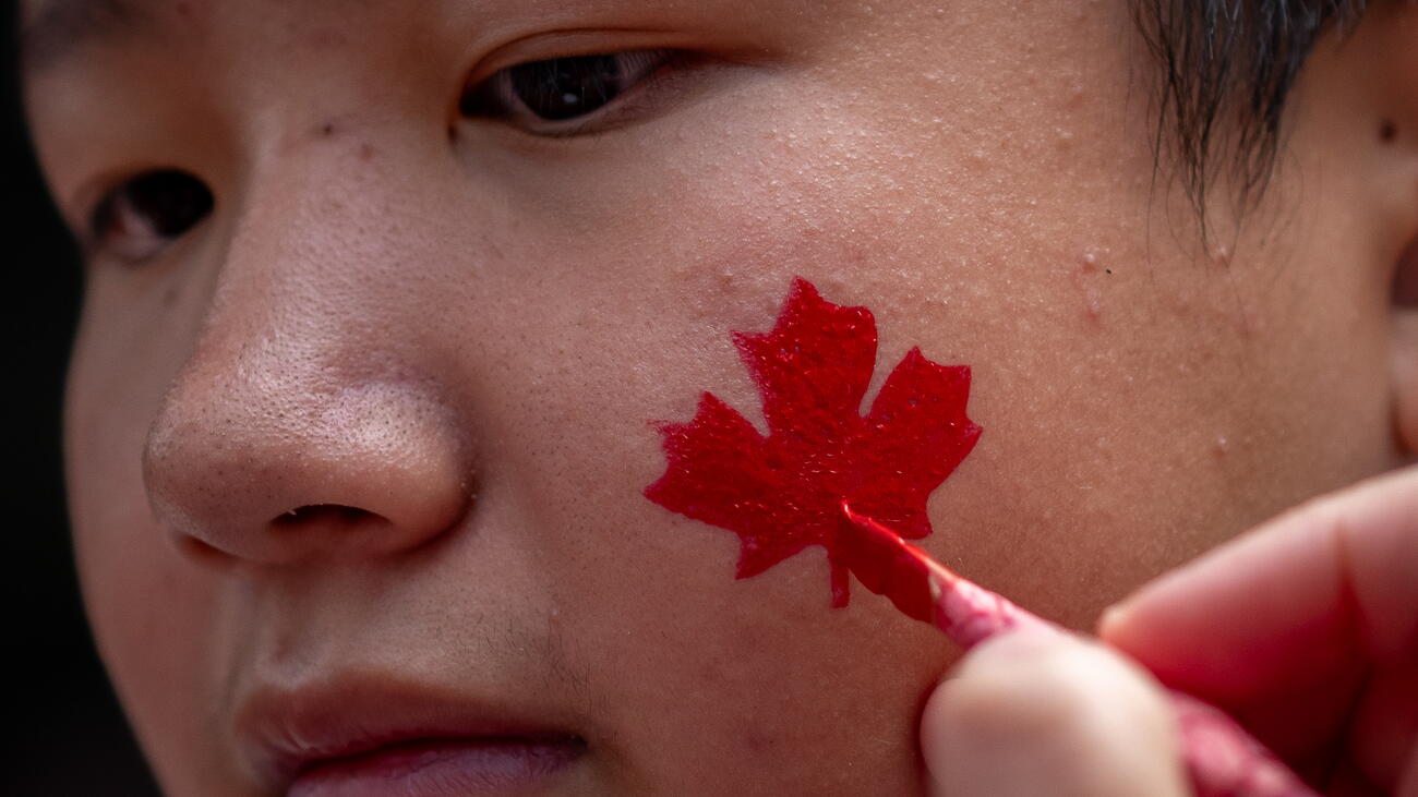 Canadian maple leaf being painted on boy's cheek