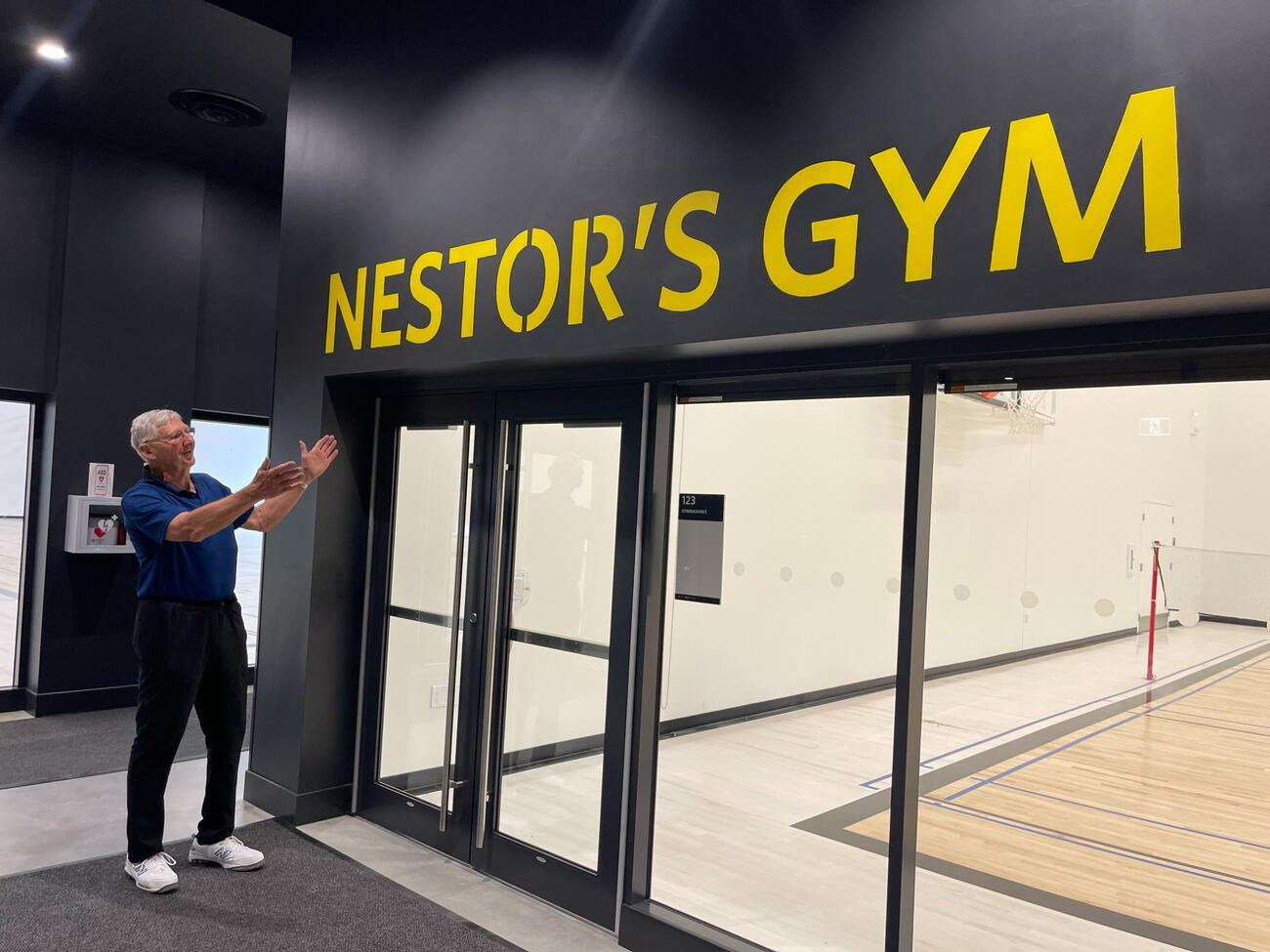 Man holds hands up to "Nestor's Gym" sign