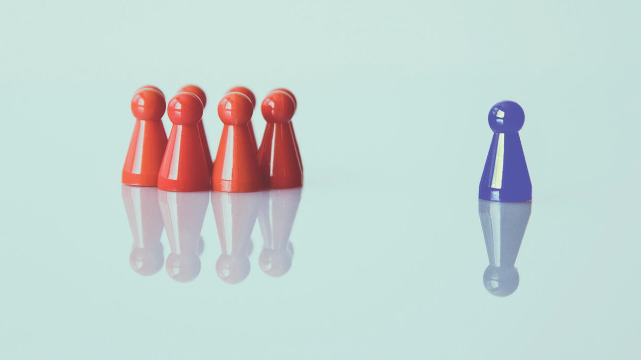 Group of red pawns clustered separately from one blue pawn